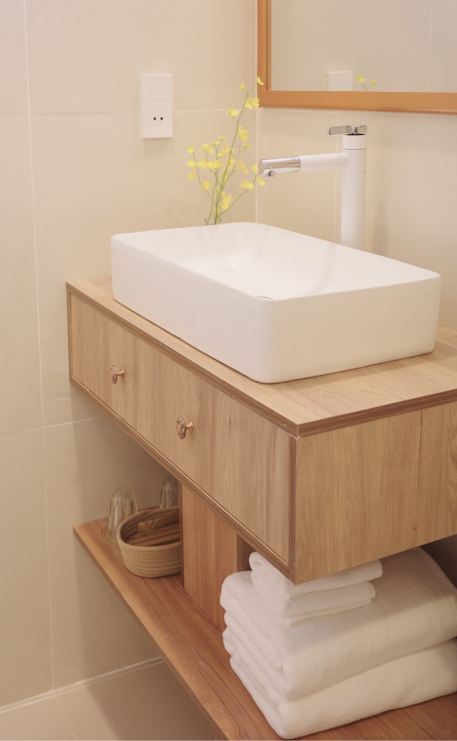 Phòng tắm với kệ gỗ và bồn rửa trắng